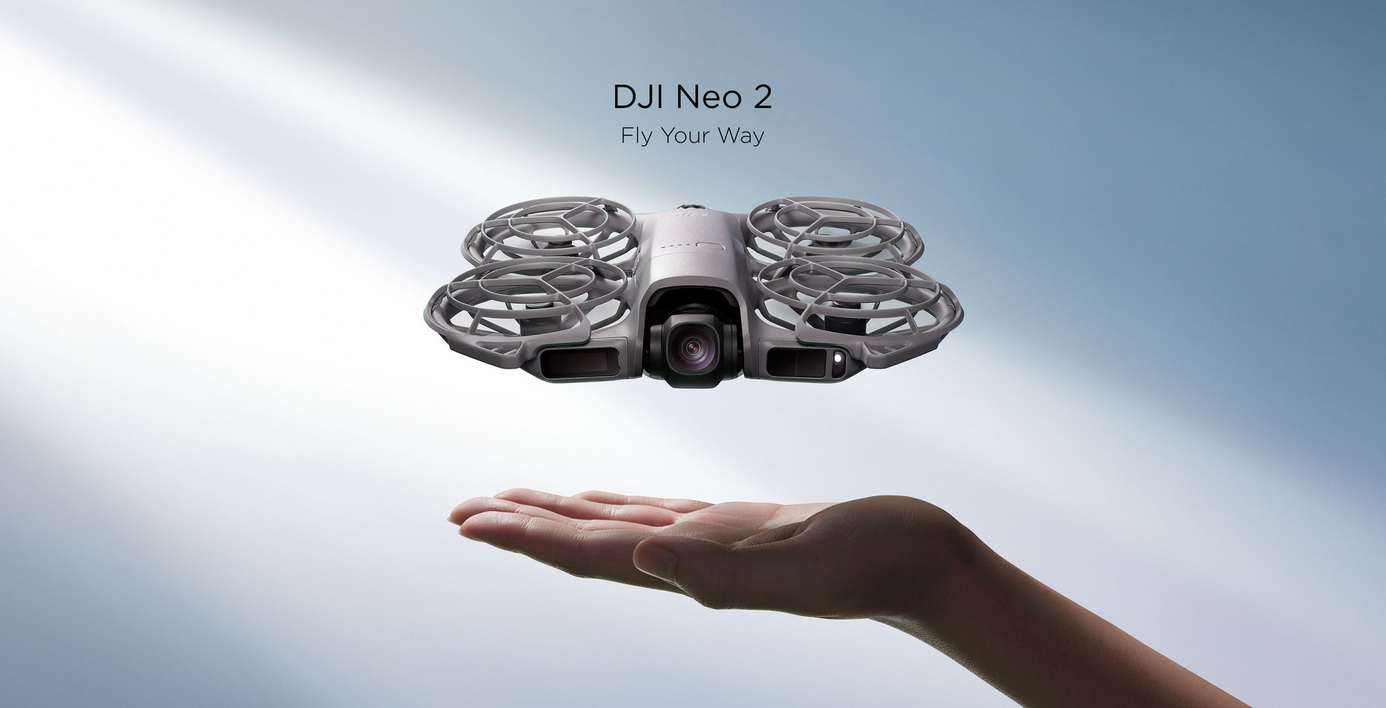 A DJI Neo 2 hovers over an open palm with a blue background. Text above says "DJI Neo 2, Fly Your Way"