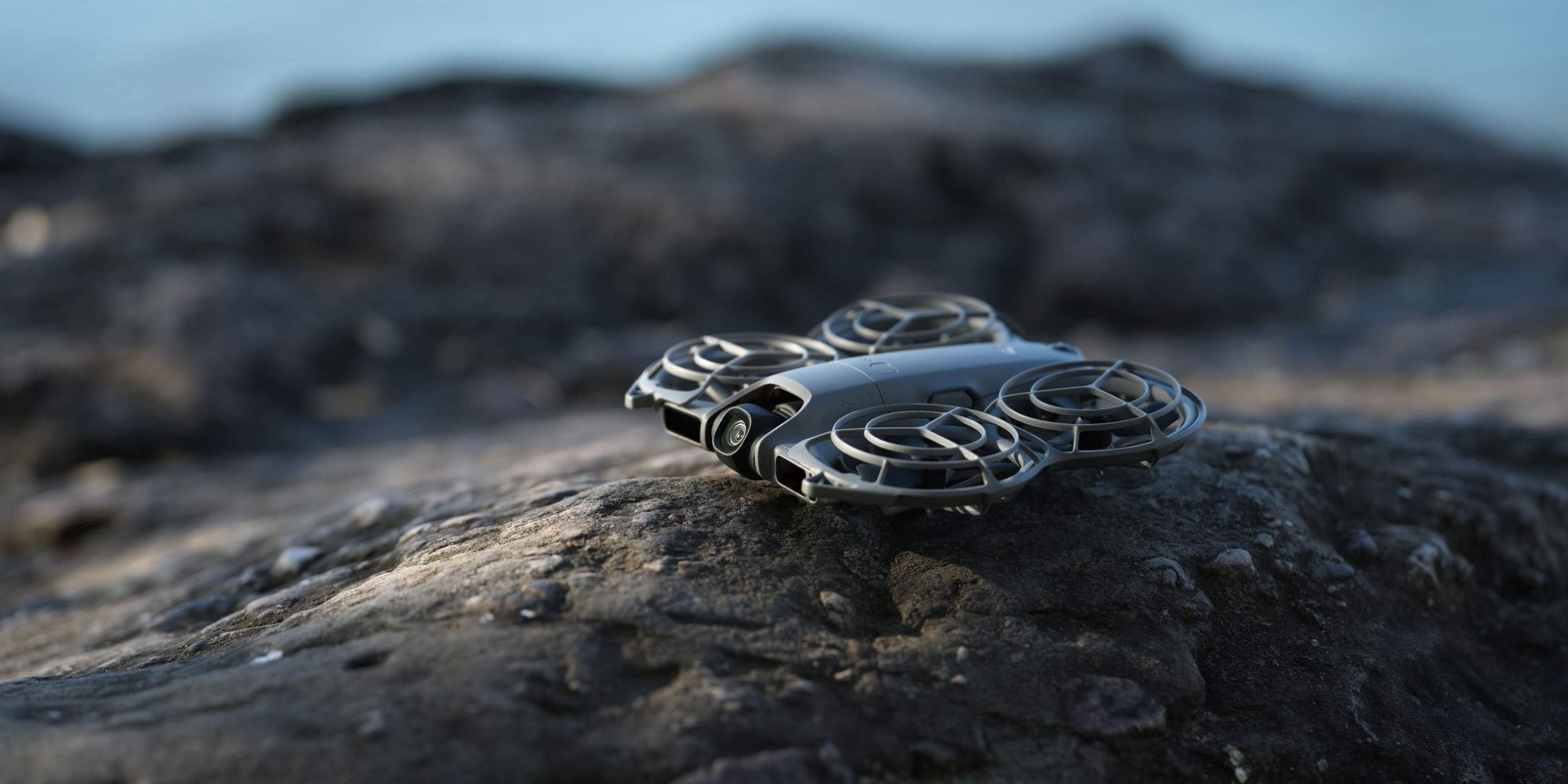 DJI Neo 2 on a rock near water.