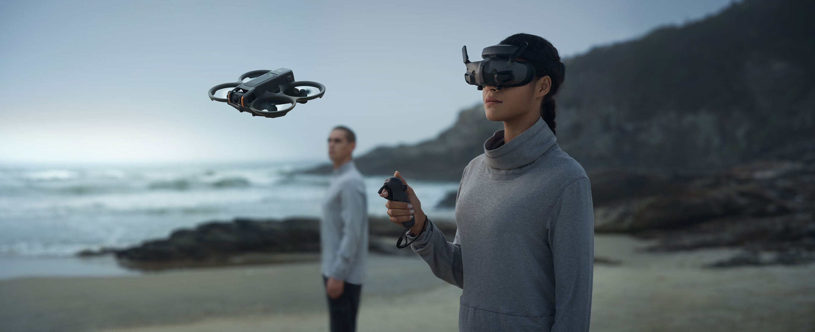 A person flies the DJI Avata 2 on a beach while using DJI Goggles 3 and the DJI RC Motion 3.