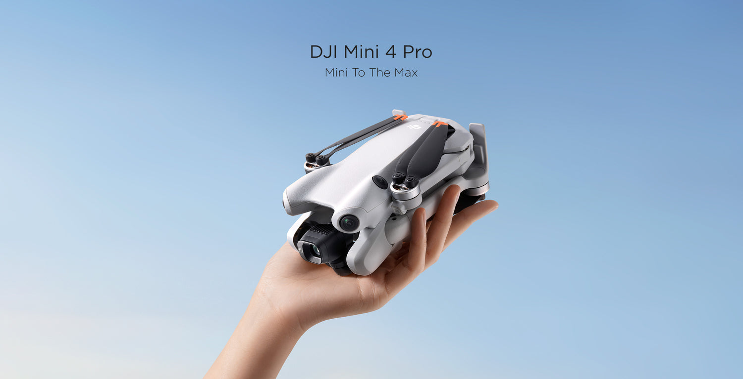 A hand holds a folded DJI Mini 4 Pro against a blue sky.