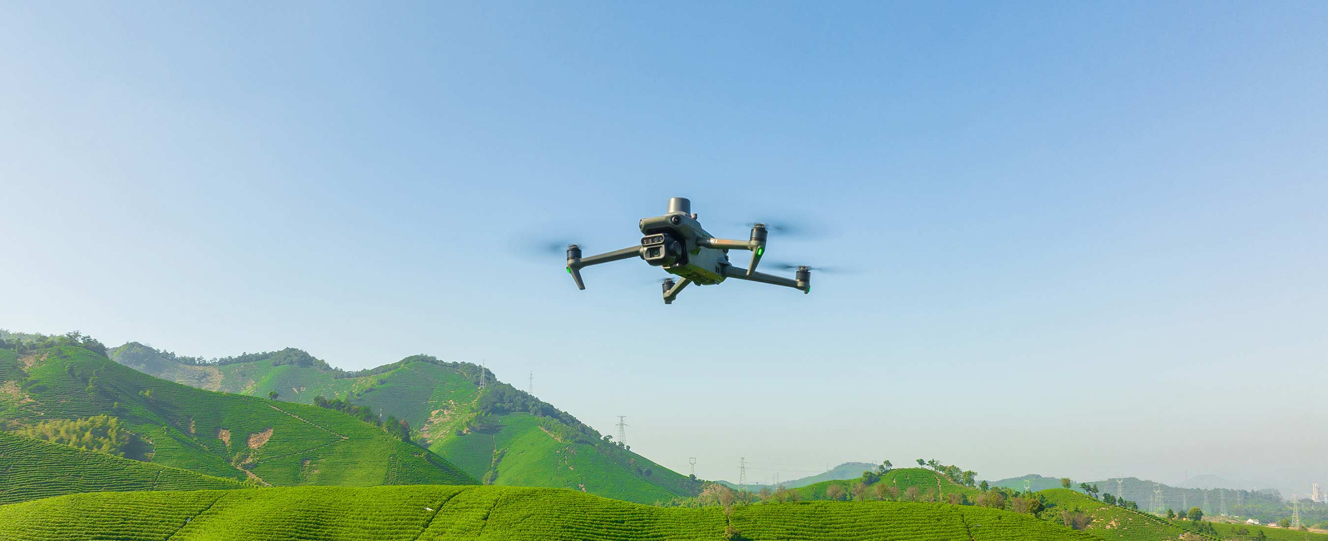 The Mavic 3 Multispectral flies over lush green crops on a bright sunny day.