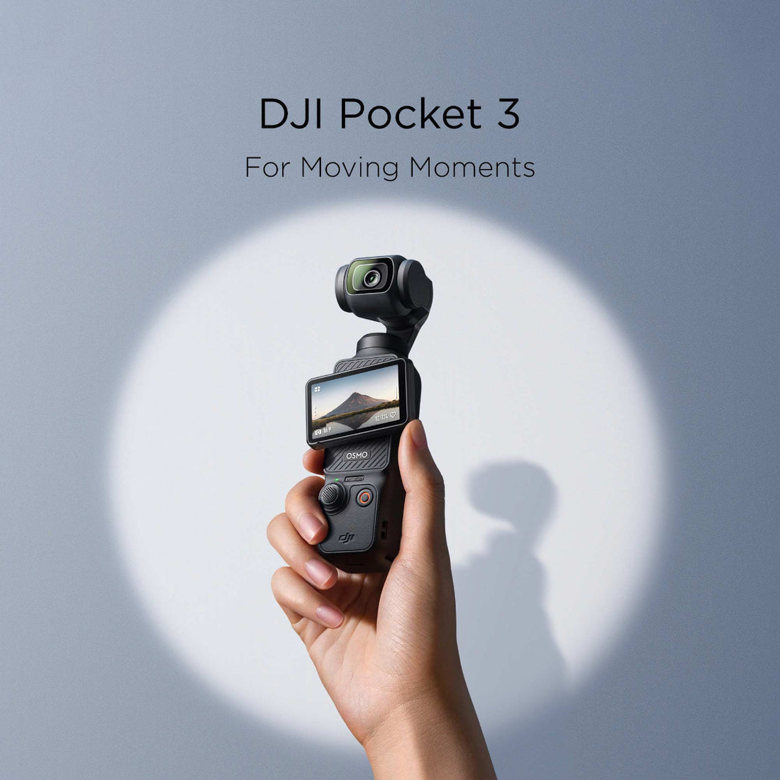 A hand holding the DJI Pocket 3 against a blue background with spotlight lighting.